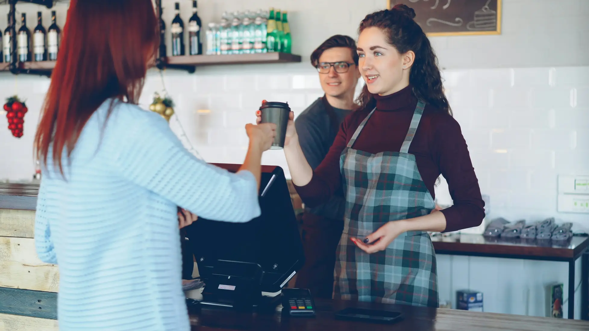 Barista handing a coffee to a customer across the counter