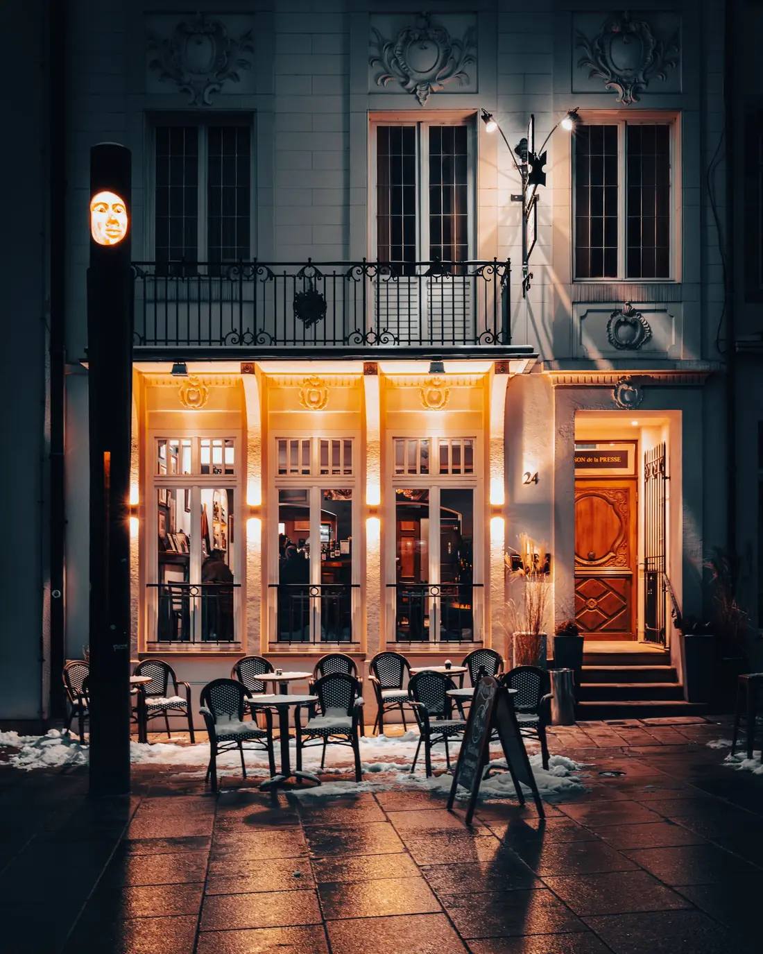 Warmly lit caf&eacute; with patio tables on a snowy evening