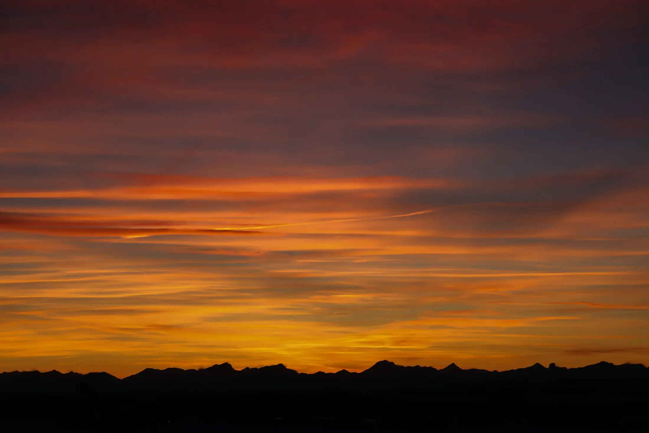 Orange sunset over a silhouetted mountain ridge