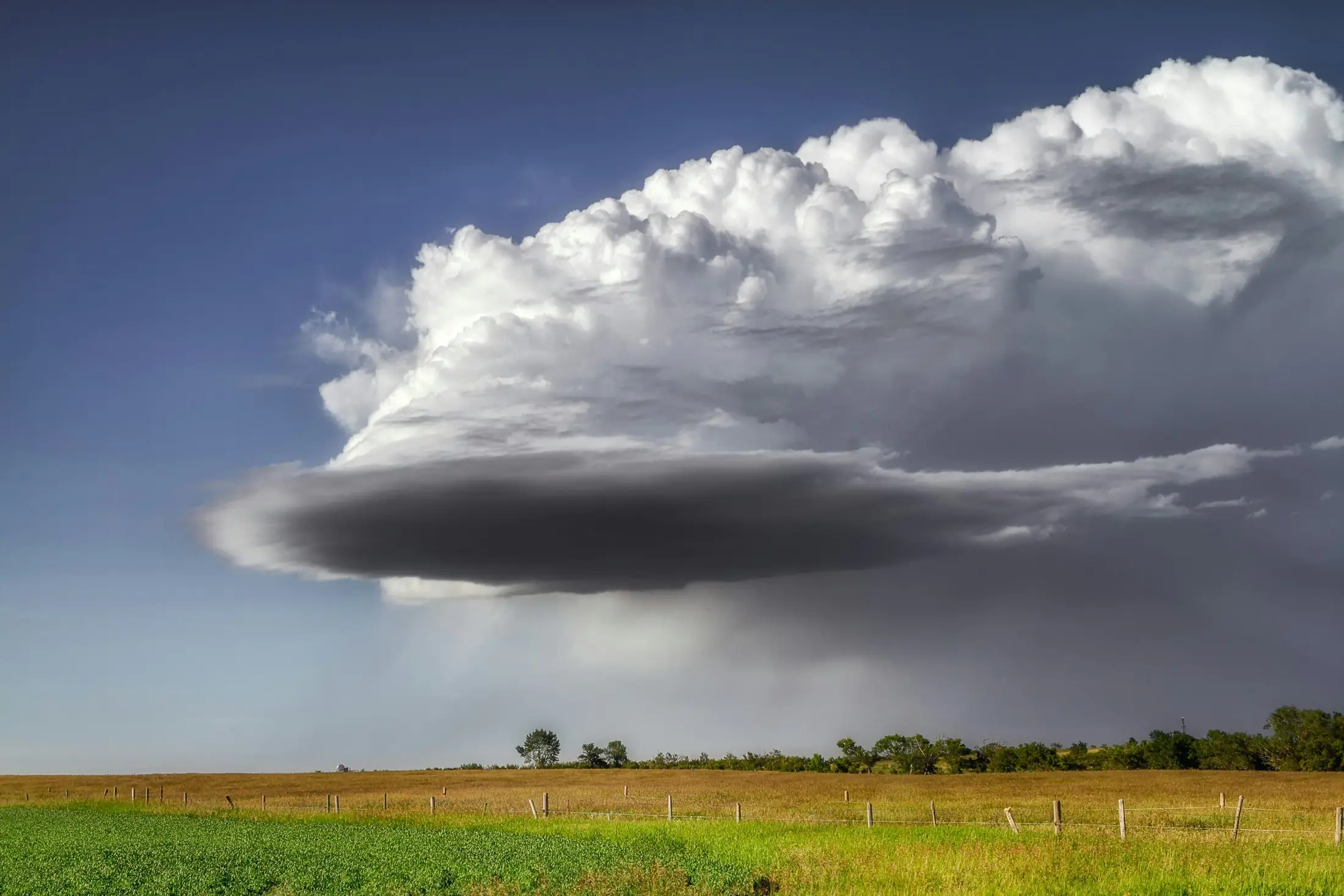Storm cloud building over open prairie pasture