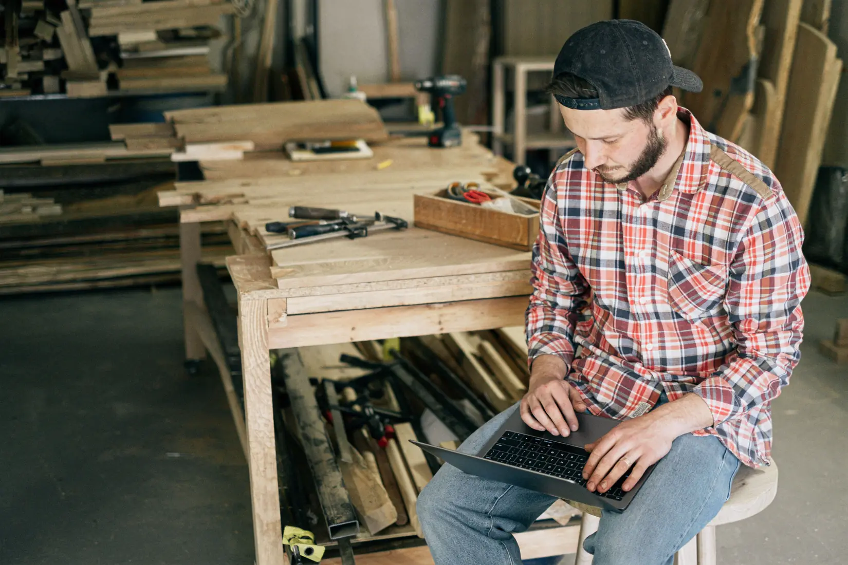 Woodworker updating his business website on a laptop in his workshop